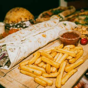 Close-up of a hearty Turkish wrap served with crispy fries and dipping sauce.