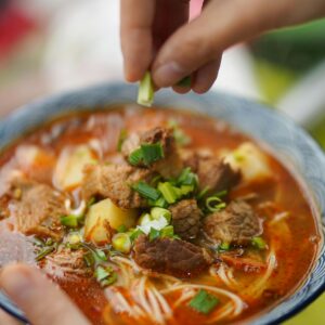 Delicious spicy beef noodle soup garnished with fresh green onions, perfect for homemade meals.